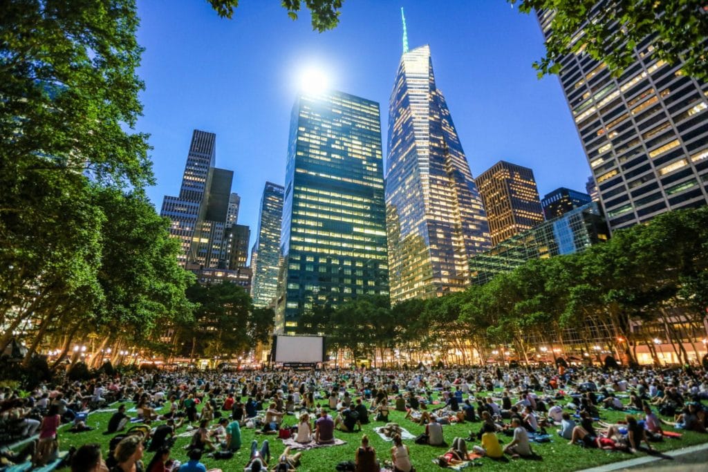a large crowd getting ready for one of Bryant Park's movie nights in the summer
