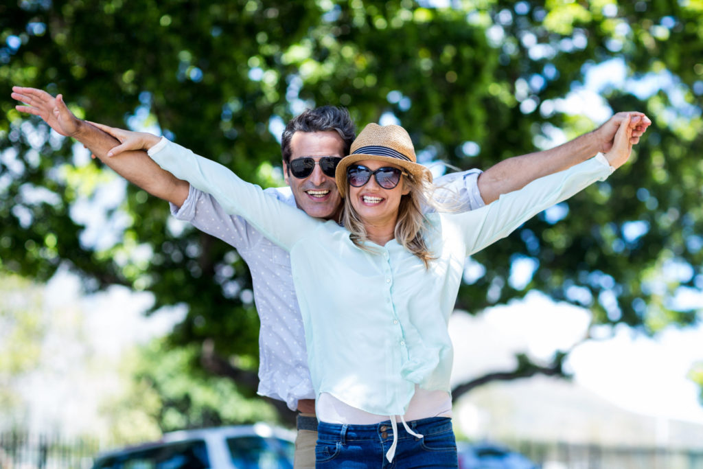 Couple with arms outstretched standing on street
